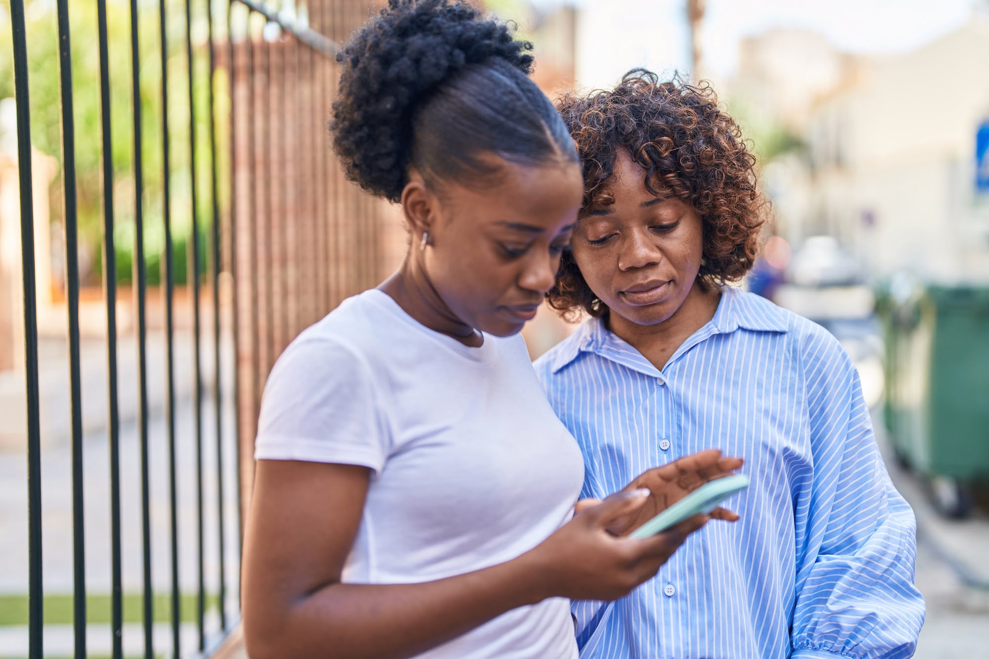 African american women mother and daughter using smartphone at street